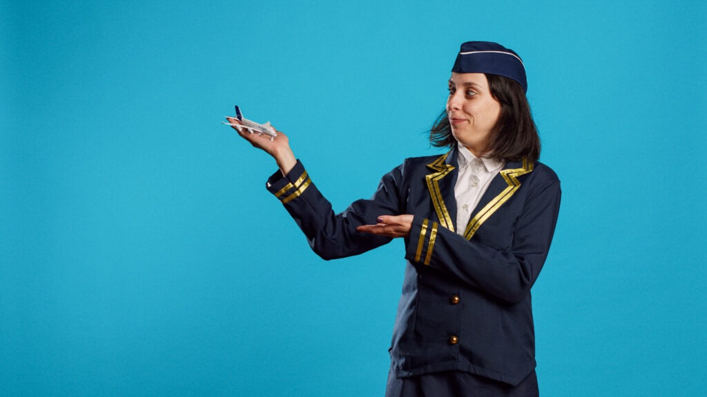 smiling stewardess showing artificial plane toy feeling confident about aviation profession young pers