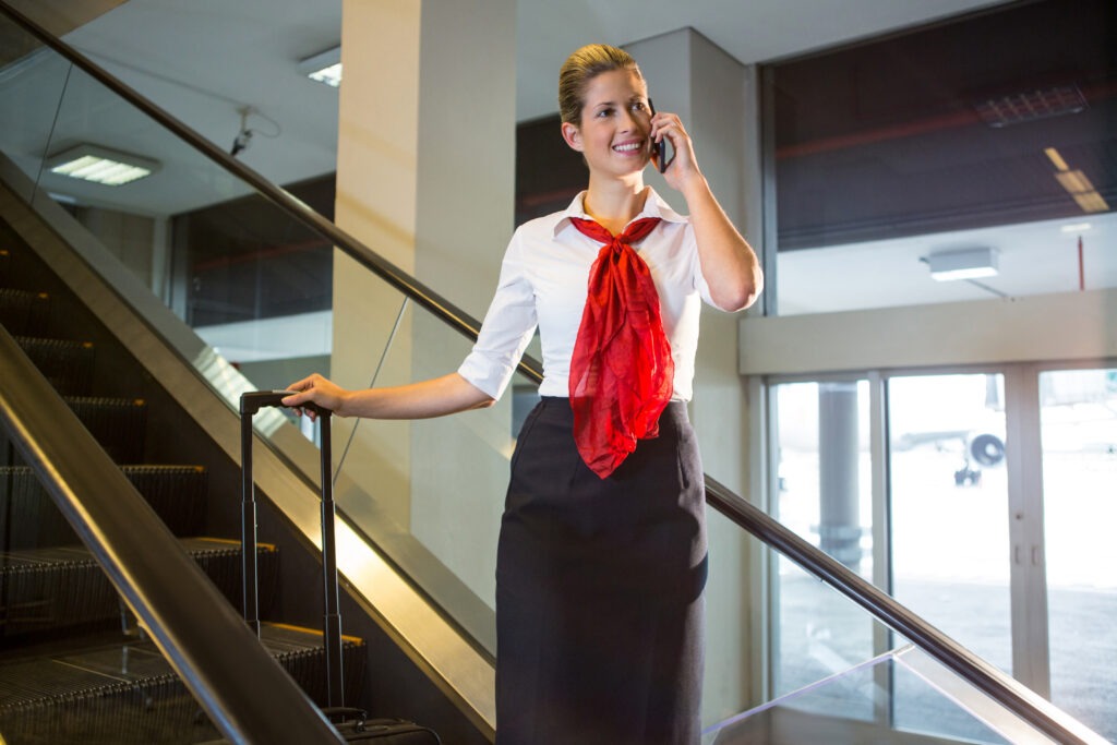 female staff with luggage talking mobile phone escalator